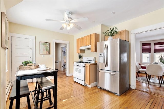 kitchen featuring ceiling fan, white gas stove, under cabinet range hood, light wood-style floors, and stainless steel fridge