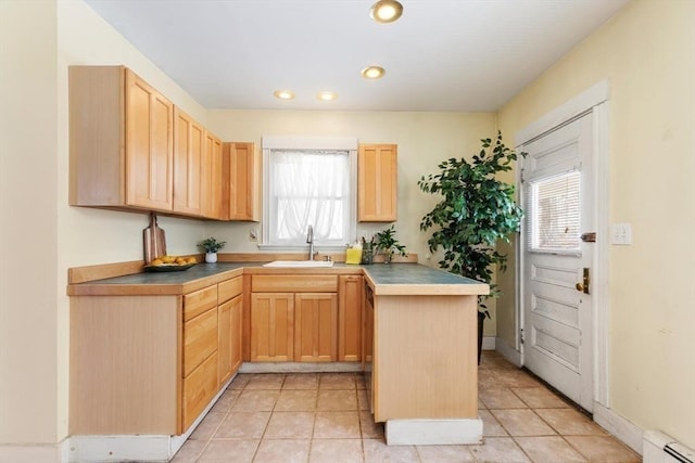 kitchen featuring a baseboard heating unit, a wealth of natural light, light brown cabinets, and a sink