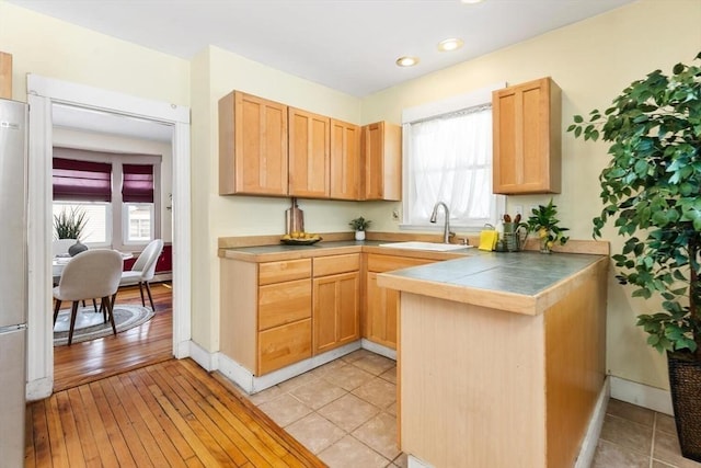 kitchen with a healthy amount of sunlight, baseboards, a sink, and light brown cabinetry