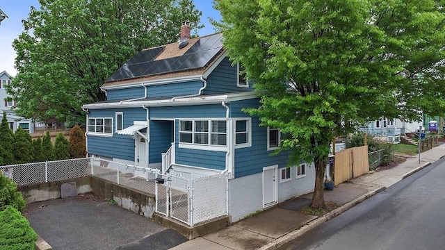 310 Lowell St, Somerville, MA 02145 - view of front of home with a chimney, solar panels, and a gate
