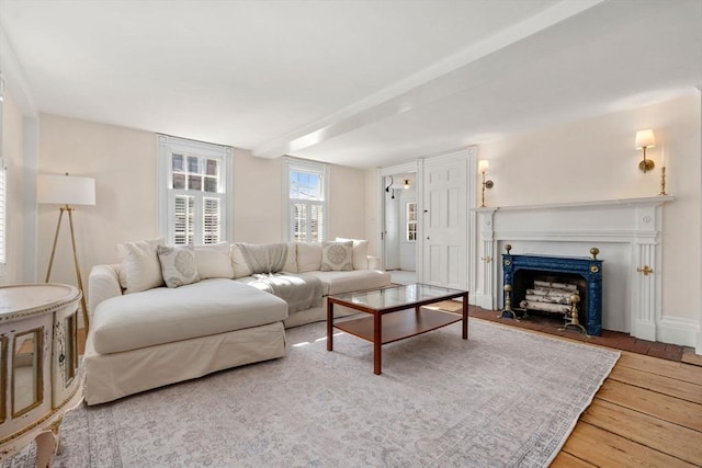 living area with baseboards, a fireplace with flush hearth, and wood finished floors