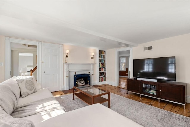 living area featuring visible vents, baseboards, a fireplace, and hardwood / wood-style flooring