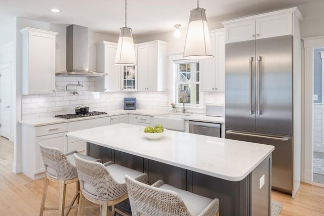 kitchen with wall chimney exhaust hood, appliances with stainless steel finishes, and white cabinets