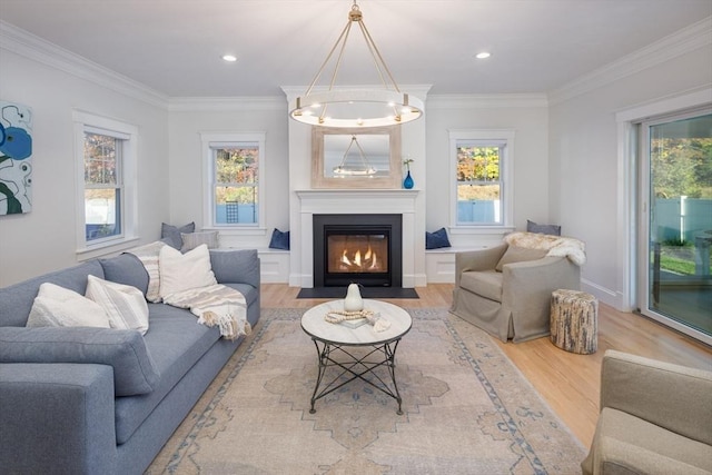 living room with a healthy amount of sunlight, light wood finished floors, a fireplace with flush hearth, and crown molding