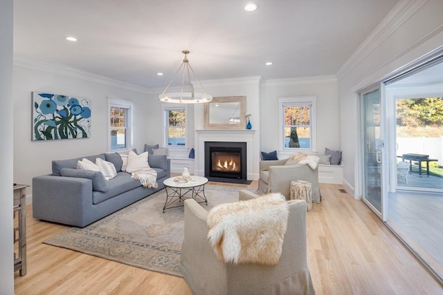 living area featuring ornamental molding, a healthy amount of sunlight, a fireplace with flush hearth, and wood finished floors