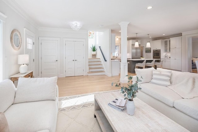 living area with light wood finished floors, recessed lighting, stairway, ornamental molding, and ornate columns