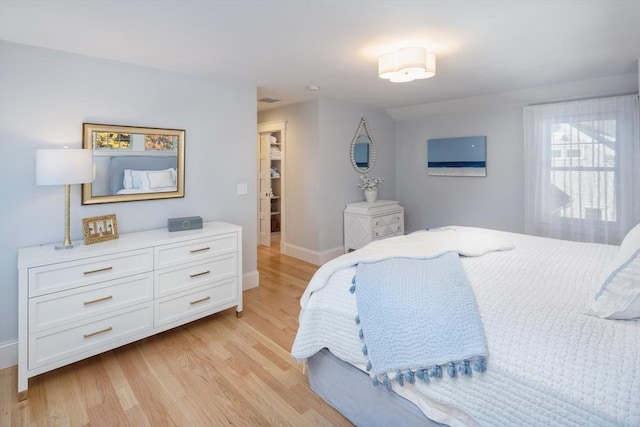 bedroom with light wood-style flooring, baseboards, and vaulted ceiling