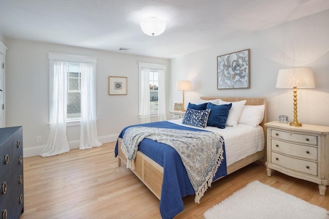 bedroom with baseboards, visible vents, and light wood finished floors