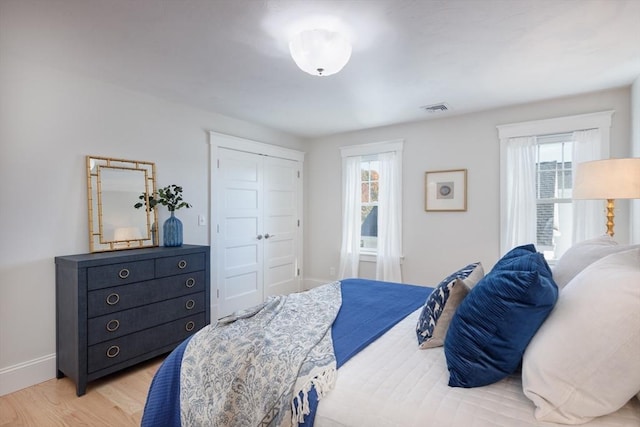 bedroom with light wood-style flooring, multiple windows, a closet, and visible vents