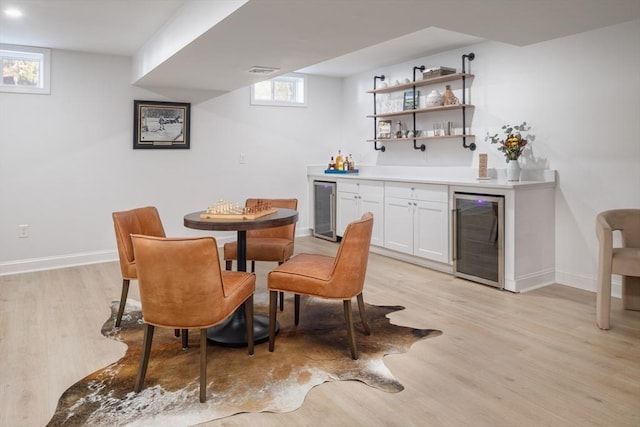 bar with wine cooler, a dry bar, and light wood-style floors