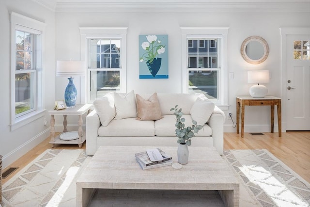 living area with light wood-style floors, visible vents, crown molding, and baseboards