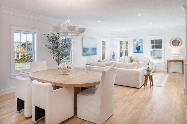 dining room with light wood-style floors, ornamental molding, and baseboards