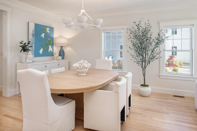 dining room with a chandelier, light wood-style floors, baseboards, and crown molding