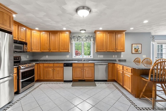 75 Birchwood Rd, Tewksbury, MA 01876 - kitchen featuring appliances with stainless steel finishes, a peninsula, healthy amount of natural light, recessed lighting, and a breakfast bar