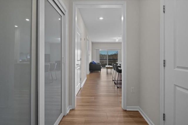 corridor with light wood finished floors and baseboards