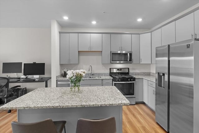 kitchen featuring a sink, gray cabinets, light wood finished floors, and stainless steel appliances