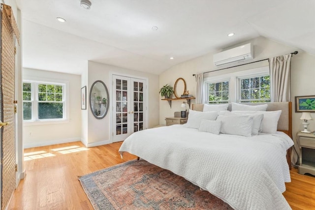 bedroom featuring french doors, light wood-style floors, a wall mounted AC, and multiple windows