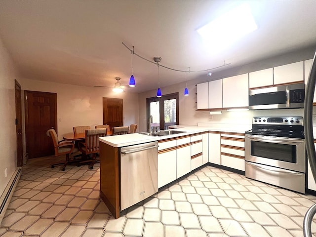 kitchen featuring white cabinets, sink, hanging light fixtures, appliances with stainless steel finishes, and kitchen peninsula