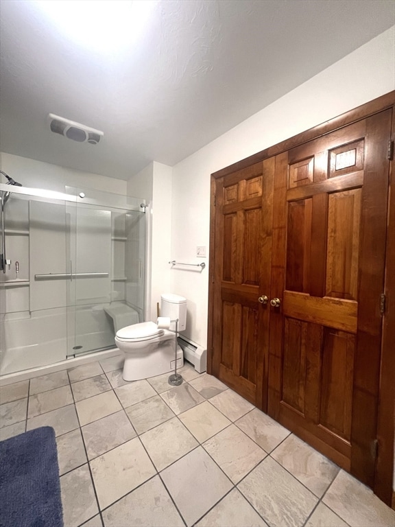 bathroom with tile patterned floors, toilet, baseboard heating, and a shower with shower door