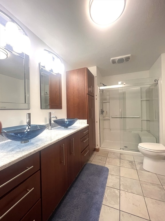 bathroom featuring tile patterned flooring, vanity, toilet, and walk in shower