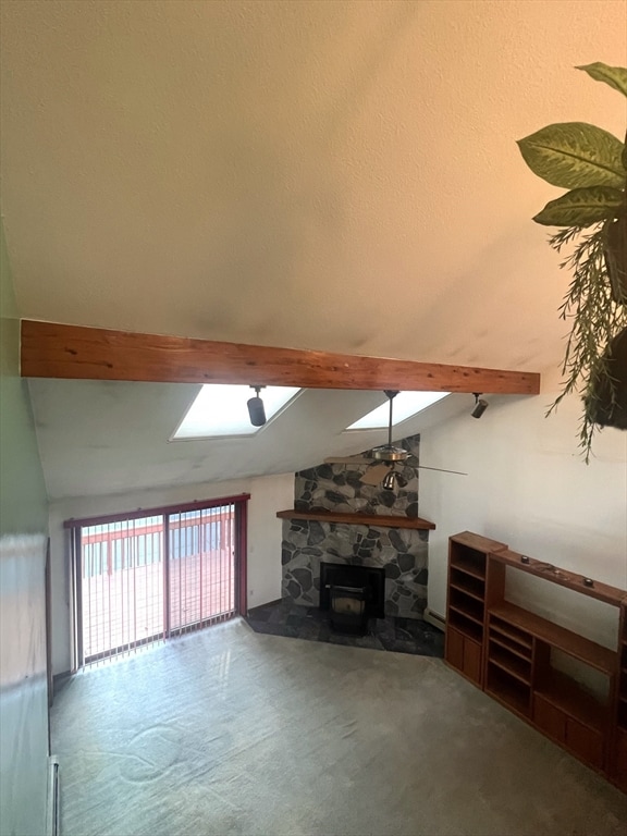 unfurnished living room with a stone fireplace, carpet floors, lofted ceiling with beams, and a textured ceiling