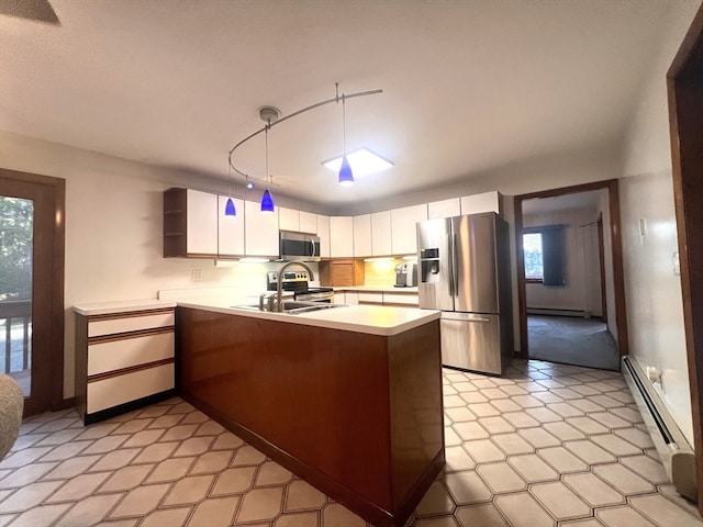 kitchen with kitchen peninsula, appliances with stainless steel finishes, decorative light fixtures, and white cabinetry