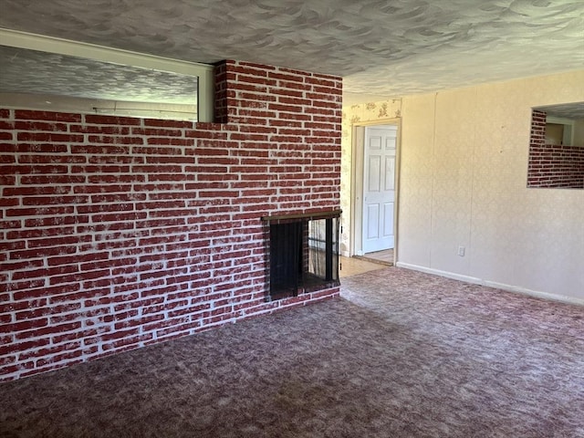unfurnished living room featuring carpet flooring, a textured ceiling, baseboards, and a fireplace