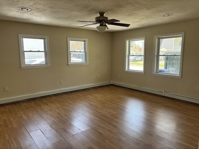 empty room featuring a textured ceiling, ceiling fan, baseboards, and wood finished floors