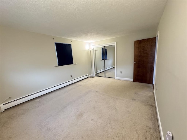 carpeted spare room featuring baseboard heating and a textured ceiling