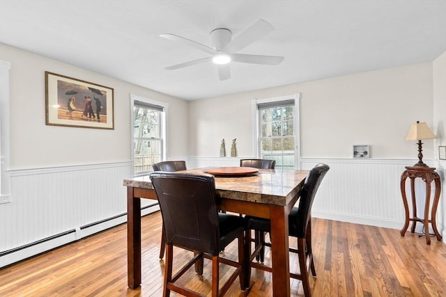 dining area with wood-type flooring, baseboard heating, plenty of natural light, and ceiling fan