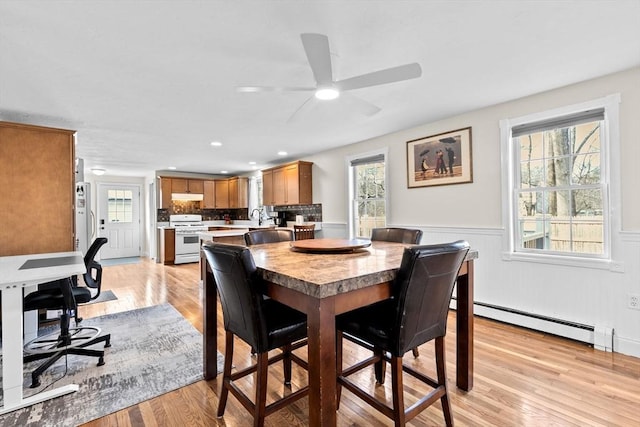 dining room featuring ceiling fan, light hardwood / wood-style floors, sink, and a baseboard radiator