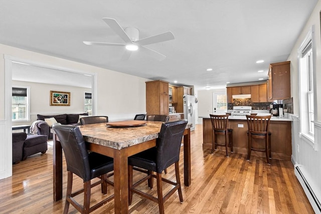 dining space featuring baseboard heating, ceiling fan, and light wood-type flooring