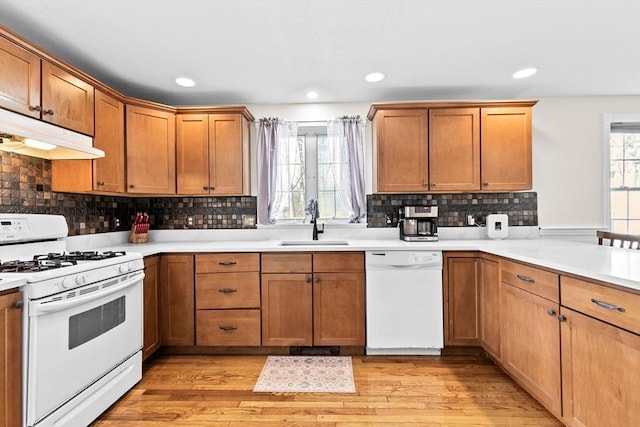 kitchen with kitchen peninsula, sink, light hardwood / wood-style floors, and white appliances