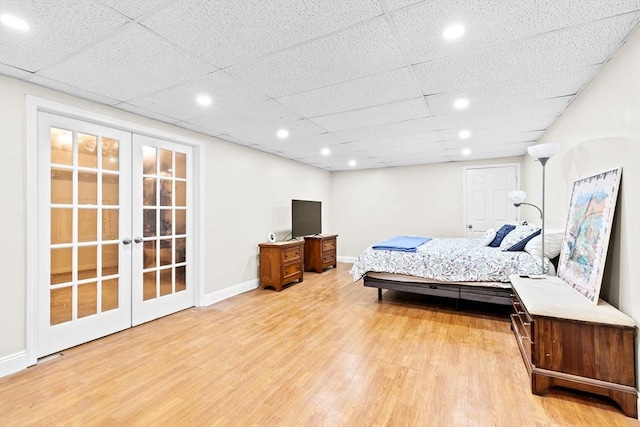 bedroom with french doors, a drop ceiling, and light wood-type flooring