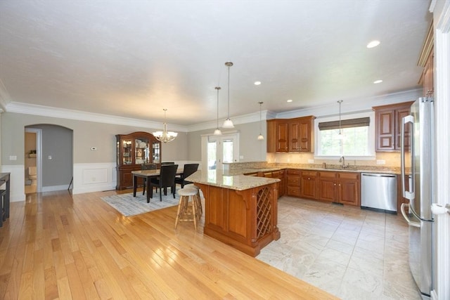 2 Powers Rd, Mendon, MA 01756 - kitchen with appliances with stainless steel finishes, a peninsula, a sink, brown cabinetry, and a breakfast bar