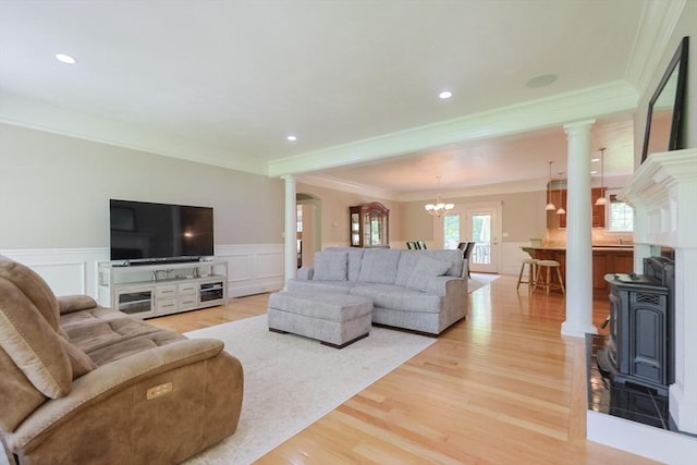 2 Powers Rd, Mendon, MA 01756 - living room featuring decorative columns, a wood stove, light wood-style floors, ornamental molding, and a chandelier