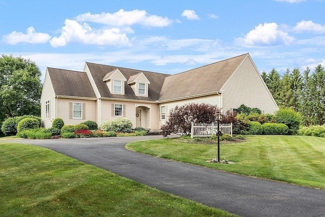 cape cod home featuring aphalt driveway and a front lawn