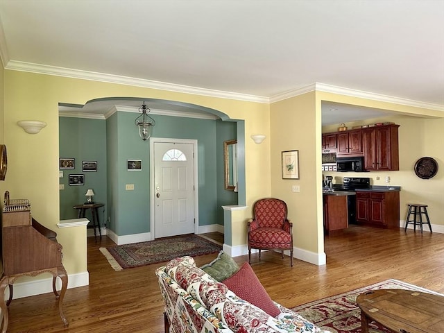 living room with baseboards, arched walkways, wood finished floors, and crown molding