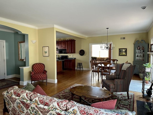 living room featuring visible vents, ornamental molding, wood finished floors, arched walkways, and a notable chandelier