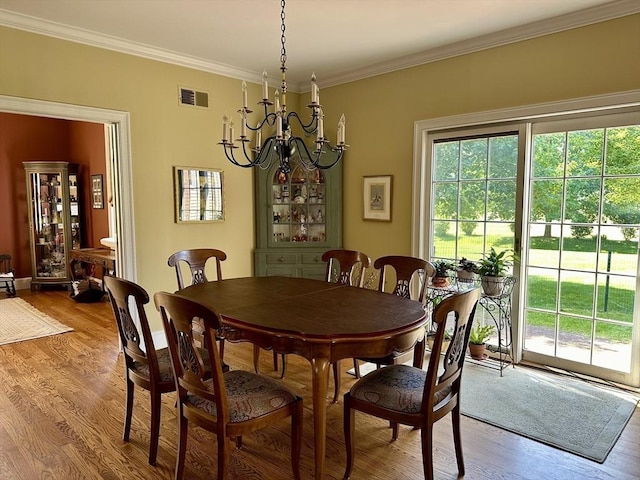 dining space with a chandelier, visible vents, light wood-style flooring, and ornamental molding