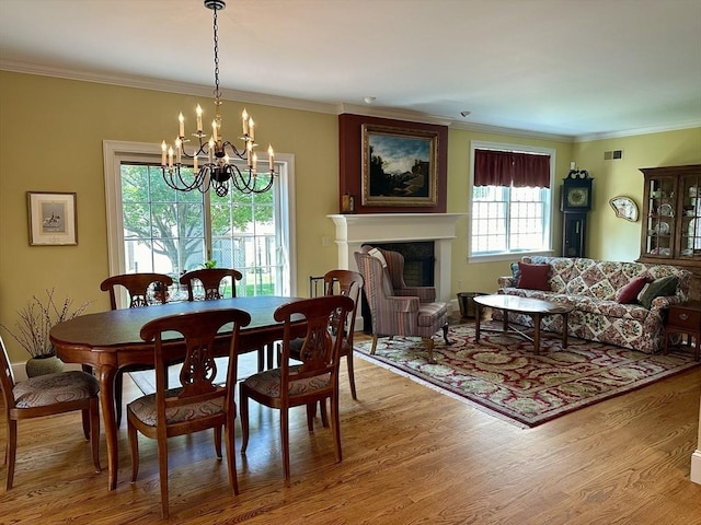 dining space featuring visible vents, light wood-style floors, a fireplace, and crown molding