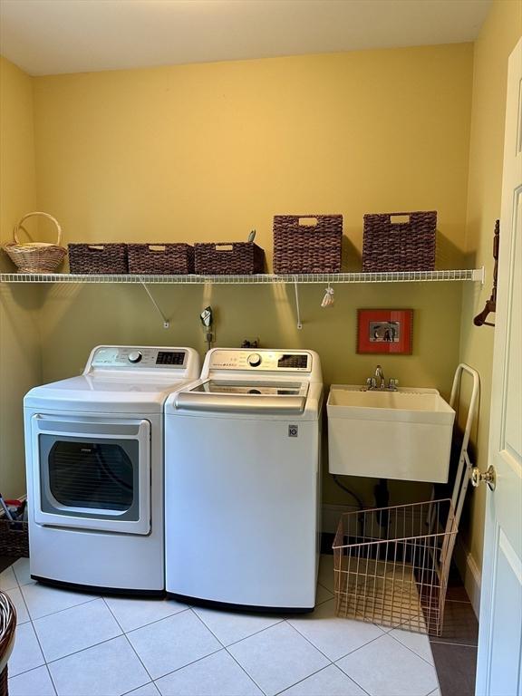 laundry room with a sink, light tile patterned floors, laundry area, and washer and clothes dryer