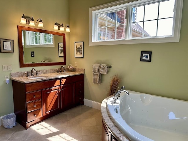 bathroom with baseboards, a garden tub, double vanity, tile patterned floors, and a sink