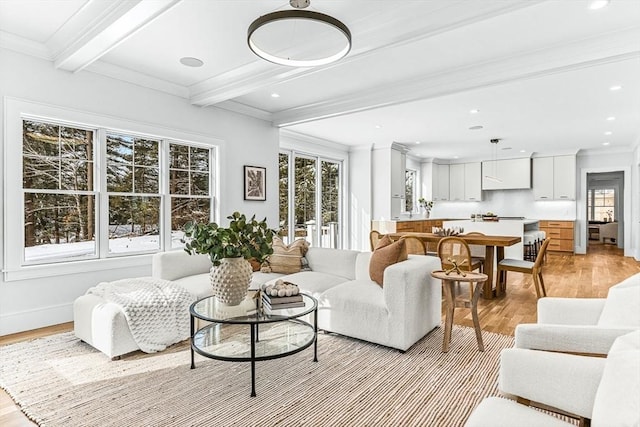 living room featuring a healthy amount of sunlight, light hardwood / wood-style flooring, ornamental molding, and beamed ceiling