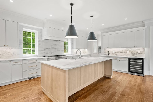 61 Heath St, Brookline, MA 02445 - kitchen with wine cooler, an island with sink, tasteful backsplash, ornamental molding, and light wood-style floors