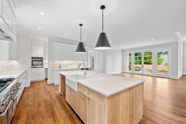 61 Heath St, Brookline, MA 02445 - kitchen with a sink, oven, light wood finished floors, backsplash, and a center island with sink