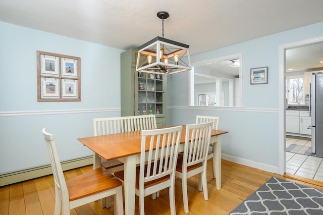 dining area featuring an inviting chandelier, light wood-type flooring, and a baseboard radiator