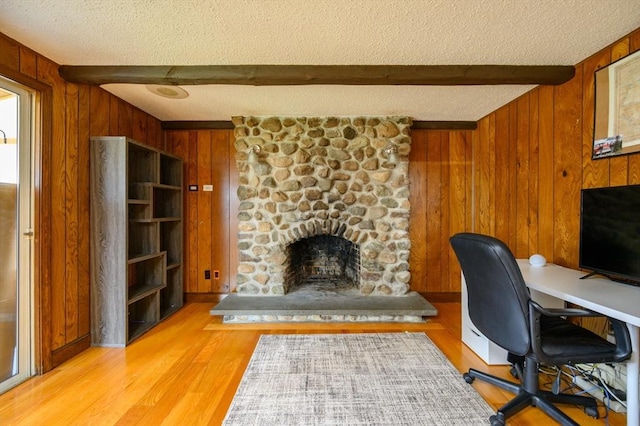 office with a fireplace, beam ceiling, and wood walls