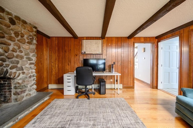 office featuring a textured ceiling, beam ceiling, a baseboard radiator, light hardwood / wood-style flooring, and wood walls