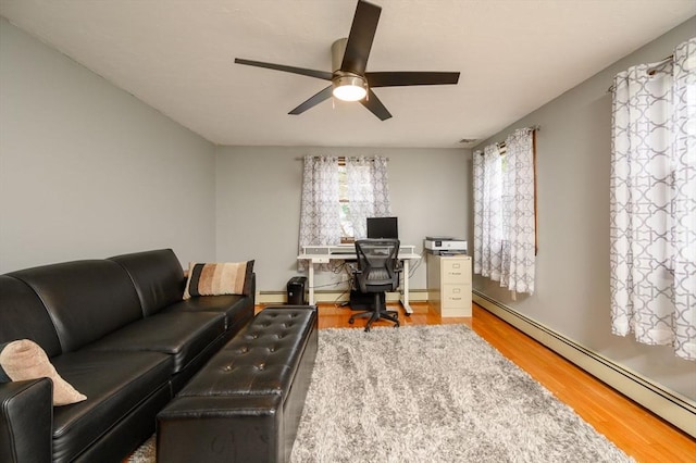 office area with ceiling fan, a baseboard radiator, and hardwood / wood-style flooring